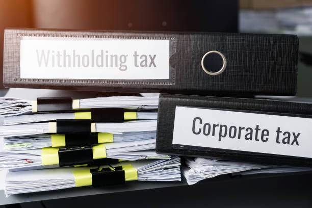 Corporate Tax UAE, Withholding taxes binders files on document report in business office. Retention taxes is income tax to be paid to UAE government by payer of income rather than by recipient of the income.